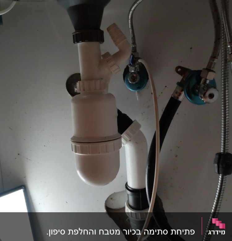 צנרת פלסטיק לבנה מתחת לכיור עם ברזים